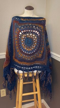 a crocheted shawl draped on top of a stool