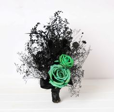 a bouquet of black and green flowers on a white table