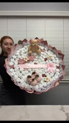 a woman is holding a large cake with teddy bears on it and baby shoes in the middle