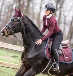 a woman riding on the back of a black horse