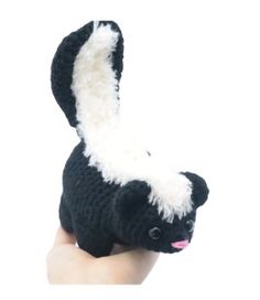 a hand holding a black and white stuffed animal