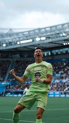 a soccer player is celebrating his goal in front of an empty stadium filled with people