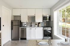 a modern kitchen with stainless steel appliances and white cabinetry, along with an open floor plan