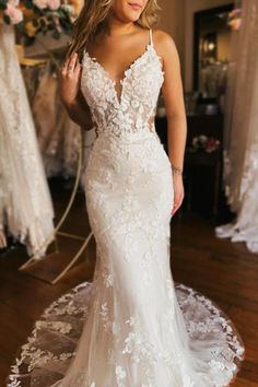 a woman standing in front of a mirror wearing a wedding dress