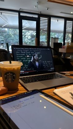 an open laptop computer sitting on top of a wooden table next to a cup of coffee