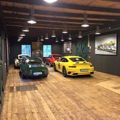 there are many cars parked in this large garage with lights on the ceiling and wood flooring