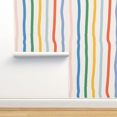 a white shelf sitting in front of a colorful striped wallpaper on a wall next to a wooden floor