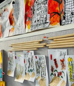 several drawings are hanging on the wall with chopsticks