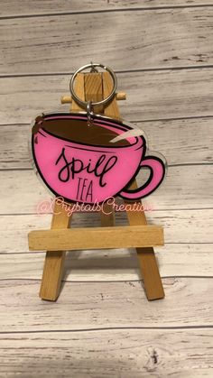 a wooden stand with a pink coffee cup on it and the word spell tea written in black