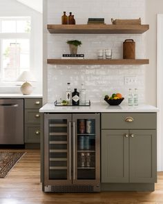 a kitchen with gray cabinets and white tile backsplash, open shelving above the sink