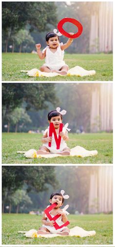 a baby sitting in the grass with a red letter