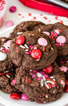 chocolate m & m cookies on a plate with sprinkles and candies