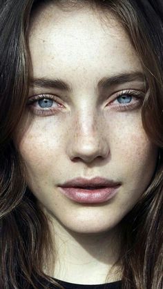 a woman with freckled hair and blue eyes looks at the camera while wearing a black shirt