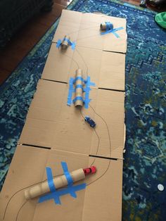 an airplane made out of cardboard sitting on top of a blue rug with tape wrapped around it