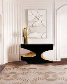 a black and gold console table in a white room with art work on the wall