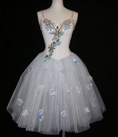 a white and blue dress with flowers on the skirt is displayed in front of a mannequin