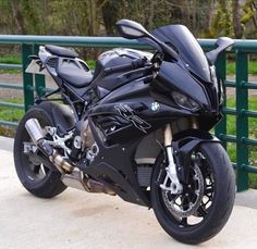 a black motorcycle parked next to a green fence