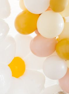 many balloons are floating in the air on a white surface with yellow and pink colors