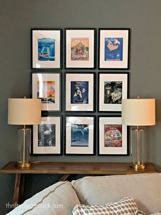 a couch with pillows and pictures on the wall above it in front of a lamp