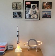 a desk with a small rocket on top of it and pictures above the table behind it