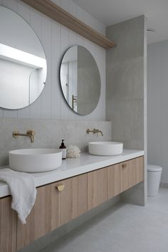 a bathroom with two sinks and mirrors on the wall next to each other in front of a toilet