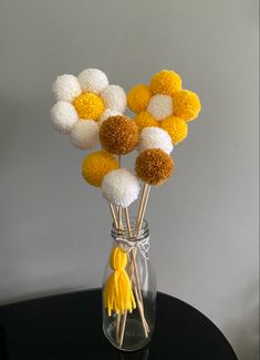 a vase filled with yellow and white pom - poms on top of a table