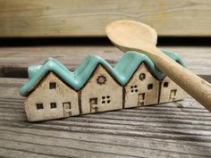 a wooden spoon sitting on top of a table next to small houses with blue roof tops