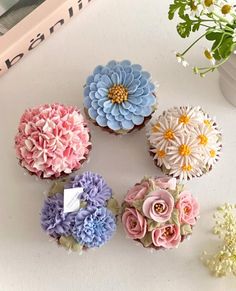 six cupcakes decorated with flowers on a table