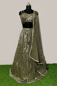 Description: - Blouse is based on net fabric and is designed in a sweetheart neckline with sleeveless with sequins and cut dana all over. Back is sheer net.The Shimmery lehenga skirt on Georgette has vertical shimmer lines and is completed with soft net attached dupatta in complementing color. Garment is chic and sophisticated. Color Golden & Mehandi Green Fabric Georgette, Net Occasion Party Wear Wedding Wear Style Lehenga Choli Work Embroidery Chest Size 38 Lehenga Length 45 Please note: Origi Sheer Georgette Party Set, Glamorous Party Choli With Mirror Work, Party Wear Sequin Net Dresses, Semi-stitched Sequined Net Lehenga, Fitted Net Lehenga With Mirror Work, Glamorous Georgette Lehenga For Party, Glamorous Party Lehenga In Georgette, Floor-length Net Lehenga With Sequins, Semi-stitched Sequin Net Dress