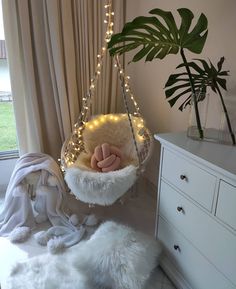 a white hammock with lights hanging from it's sides and a plant in the corner