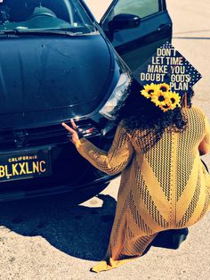 a woman in a sunflower hat leaning against a car