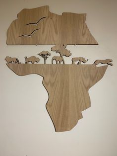 a wooden cut out of the shape of africa with elephants and giraffes