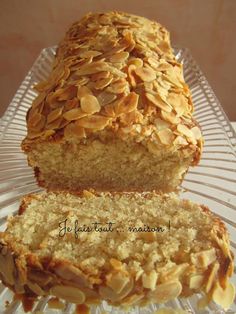 a loaf of bread sitting on top of a glass platter filled with sliced almonds