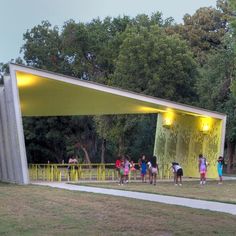 several people are standing in front of a yellow structure that is lit up at night