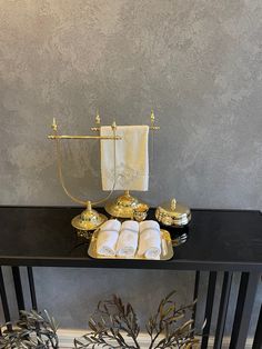 a black table topped with gold dishes and towels next to a white towel on top of it