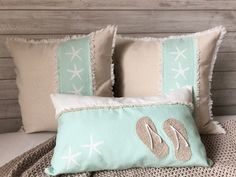 two pillows with flip flops and starfish on them are sitting on a bed