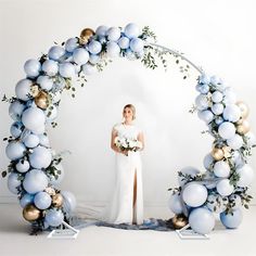 a woman standing in front of a white backdrop with blue and gold ornaments