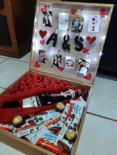 an open box filled with valentine's day candy and candies on top of a tiled floor