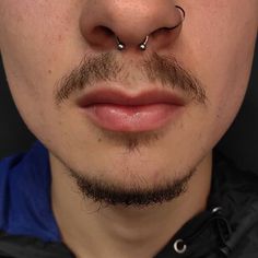 a close up of a man with a nose ring and piercing on it's nose