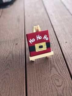 a small wooden easel with a red and black santa clause on it's back