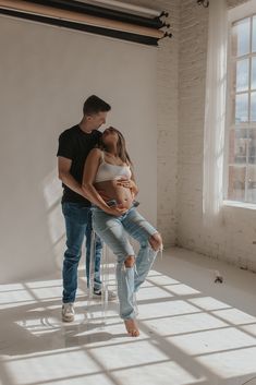 a pregnant woman sitting on top of a chair next to a man who is holding her belly