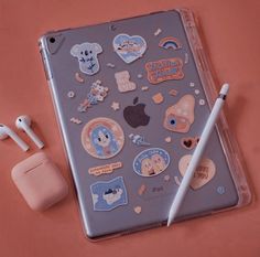 an ipad with stickers on it next to ear buds