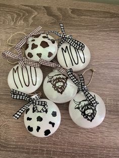 six ornaments with different designs on them sitting on a wooden table, one is white and the other is black