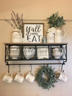 coffee mugs are hanging on the wall above a shelf