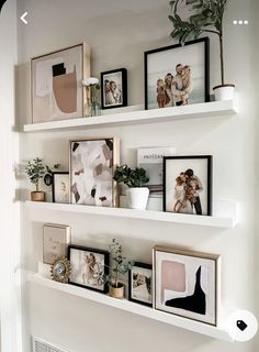 some white shelves with pictures and plants on them