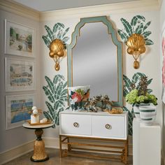 a white dresser topped with a mirror next to a wall covered in pictures and plants