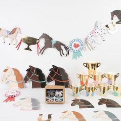 an assortment of horse themed items on display in front of a white wall with gold cups and vases