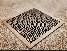 a square wooden grate sitting on top of a carpet