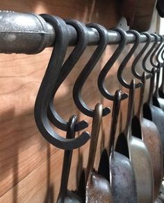 a bunch of metal hooks hanging on a wooden wall