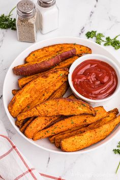 baked sweet potato wedges with ketchup in a white bowl on a marble table